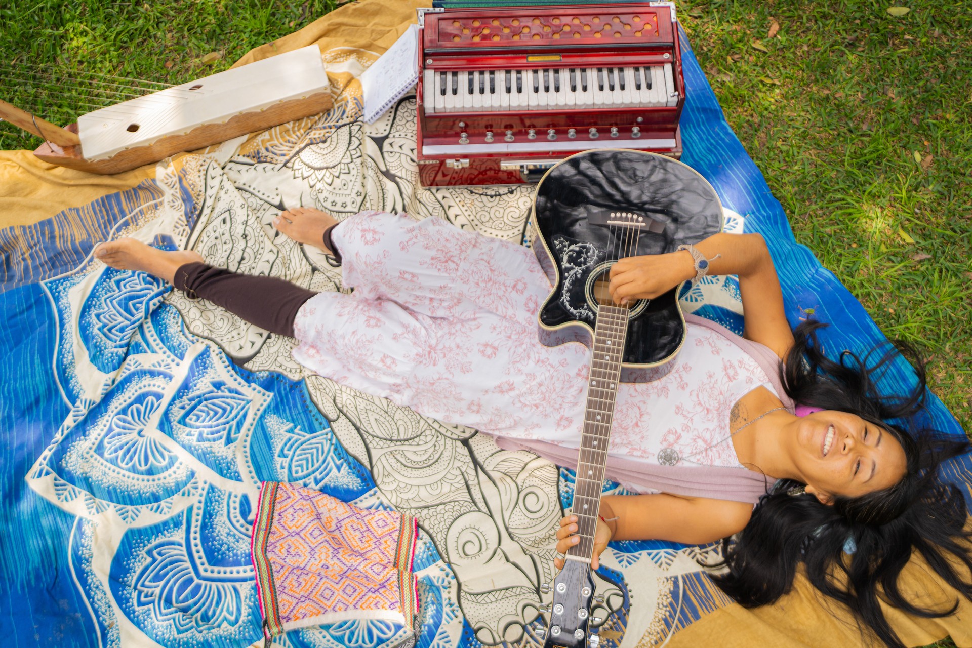 Woman lying down playing guitar in park